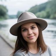 Young woman wearing a hat on a riverside path with soft daylight on the water